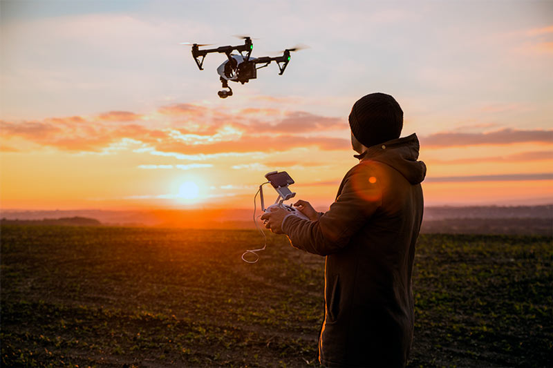 Piloto remoto operando un drone al atardecer